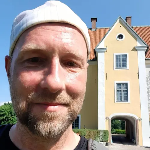 Headshot (selfie) of Johan Edlund in front of the castle Krageholm