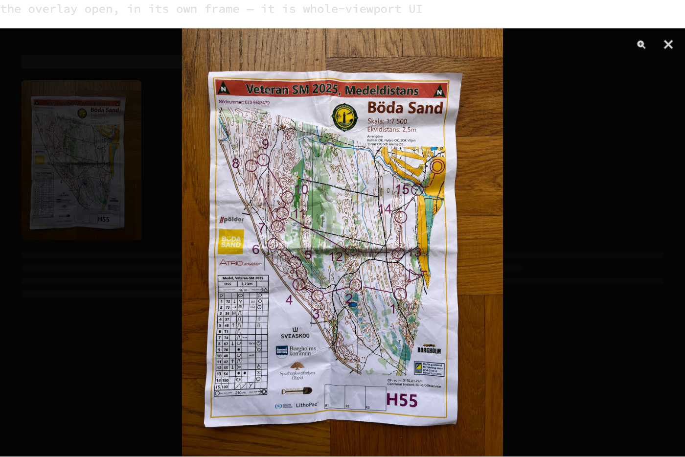 A browser-sized frame showing the lightbox open: the page dimmed behind a dark scrim, the full race map scan fitted to the height of the frame, and a zoom and a close button in the top right corner.